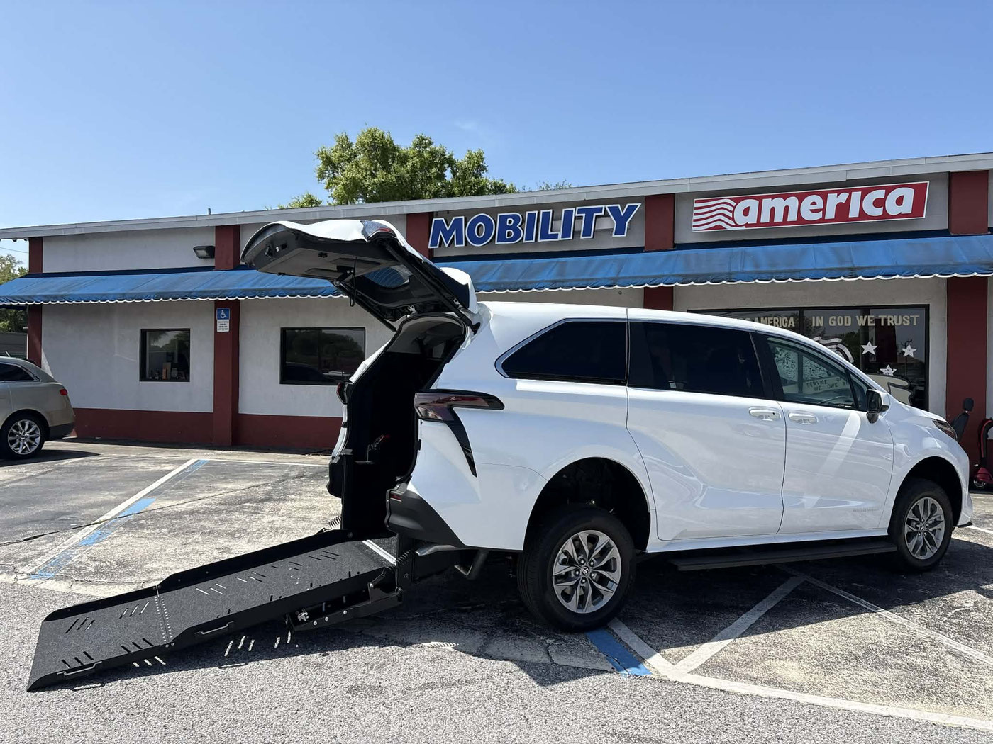 A 2026 Toyota Sienna SE with its rear-entry ramp folded down onto the pavement outside Mobility America