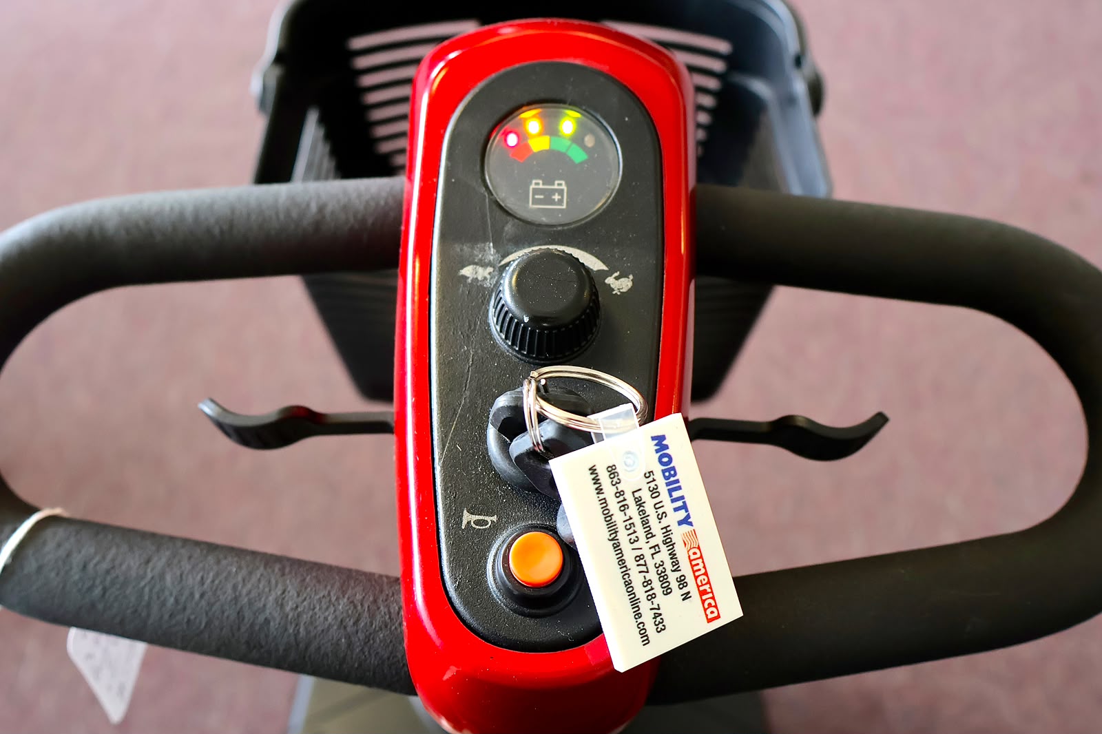 Pre-owned red Golden Buzzaround EX 3-wheel mobility scooter, photographed at the Mobility America showroom in Lakeland