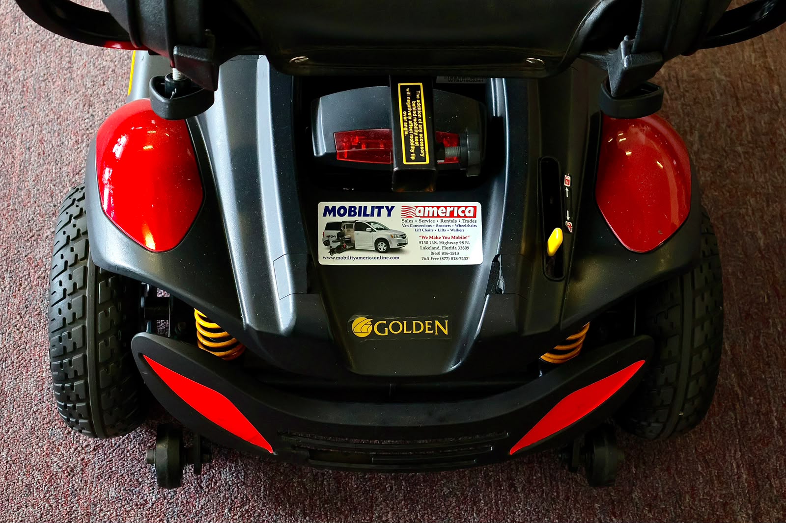 Pre-owned red Golden Buzzaround EX 3-wheel mobility scooter, photographed at the Mobility America showroom in Lakeland