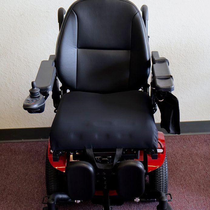 Pre-owned red Merits Vision Ultra rehab power wheelchair with manual attendant control, photographed at the Mobility America showroom in Lakeland