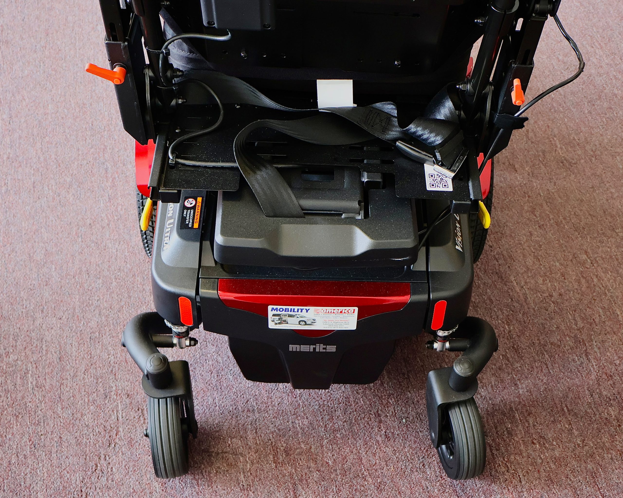 Pre-owned red Merits Vision Ultra rehab power wheelchair with manual attendant control, photographed at the Mobility America showroom in Lakeland