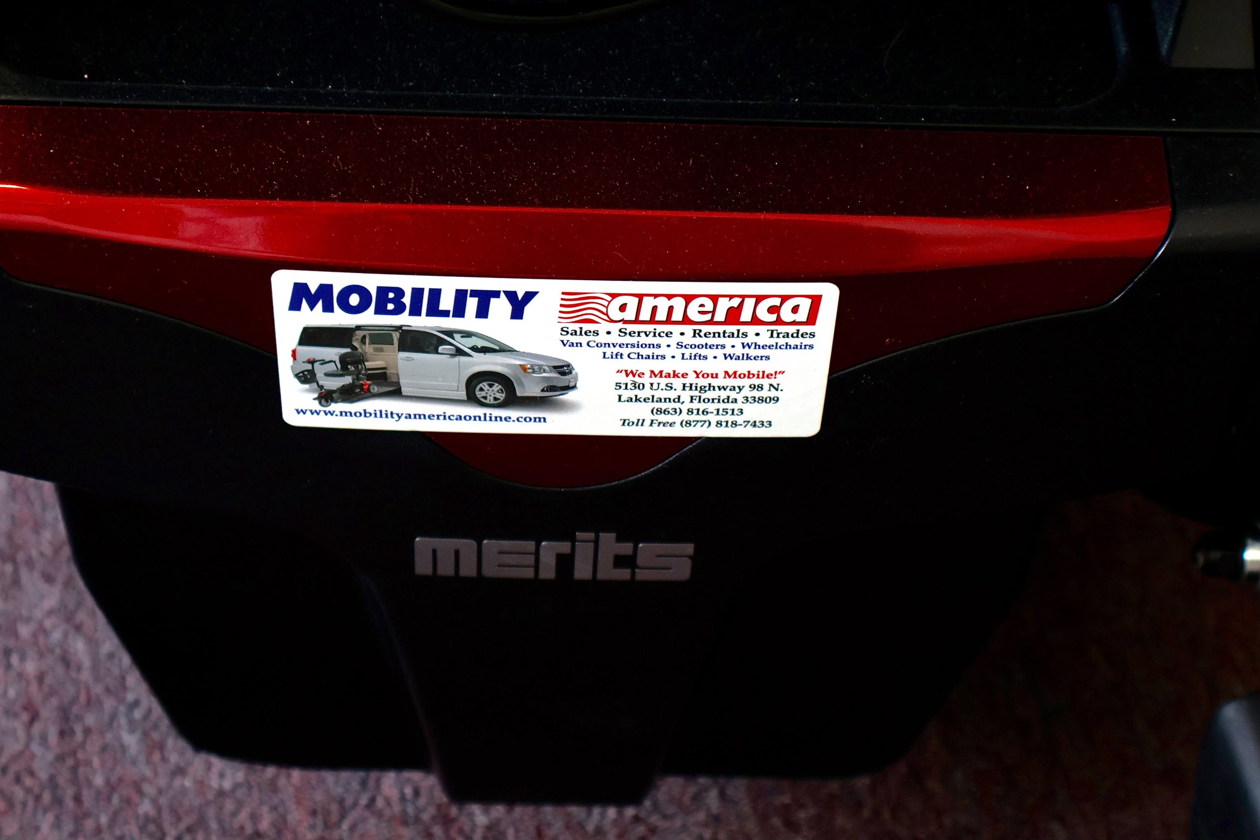 Pre-owned red Merits Vision Ultra rehab power wheelchair with manual attendant control, photographed at the Mobility America showroom in Lakeland