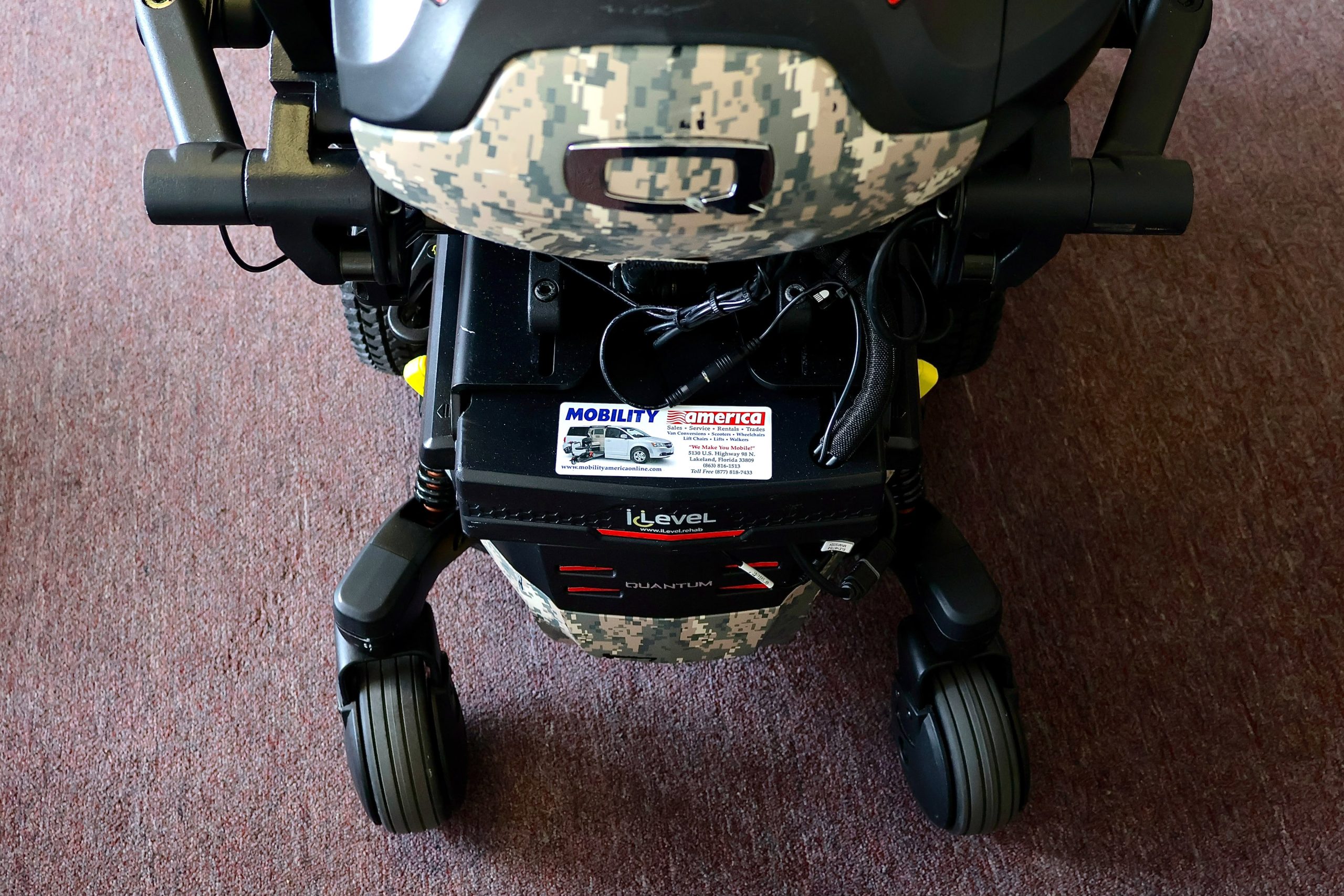 Pre-owned Quantum iLevel rehab power wheelchair in digital camo, photographed at the Mobility America showroom in Lakeland
