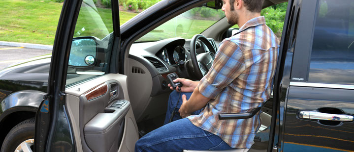 A powered transfer board lifting a person from the vehicle floor up to the driver seat