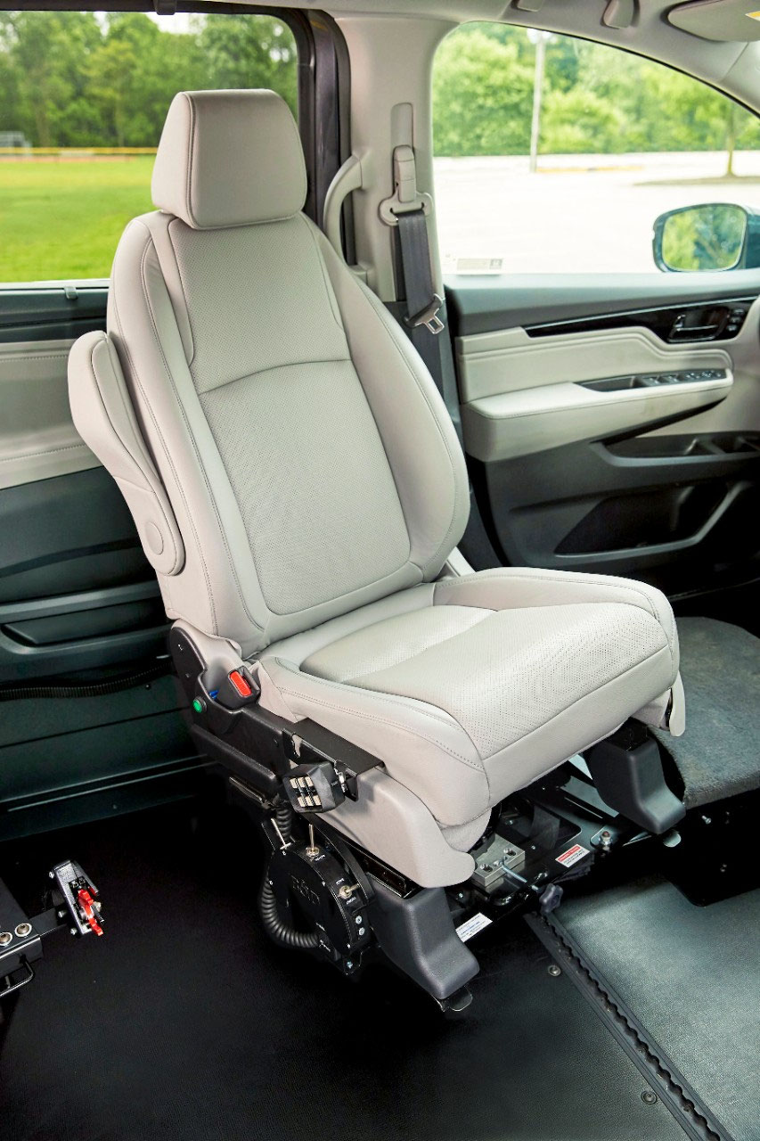 A vehicle front seat turned inward on a powered transfer base inside a lowered-floor van